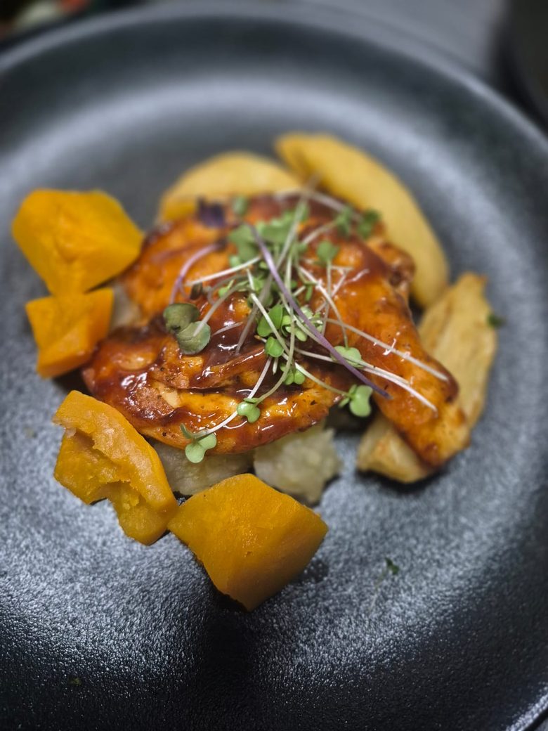 A chef-plated glazed chicken main with roast butternut and micro herbs