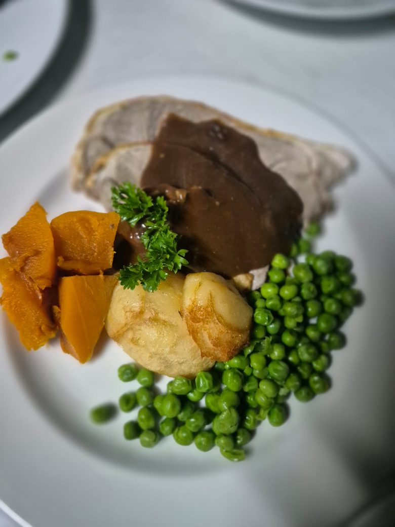 A wholesome plated meal with pork, roast butternut and peas